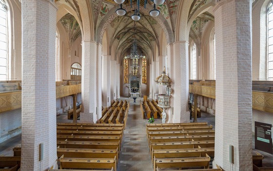Innenraum einer Kirche mit Backsteinpfeilern, Holzb&auml;nken, bemaltem Gew&ouml;lbe, Kanzel und Altar mit Buntglasfenstern., Foto: Andreas Franke, Lizenz: Andreas Franke